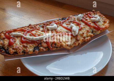 scopri il gusto della polonia con un appetitoso zapiekanka, un panino caldo su mezza baguette, abbondantemente riempito con vari condimenti, che offre una Foto Stock