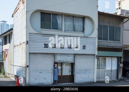 Anziana donna giapponese in piedi di fronte a casa sua, Nagoya Foto Stock
