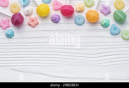 Lollipop e caramelle dolci colorati su sfondo di legno bianco. Foto Stock