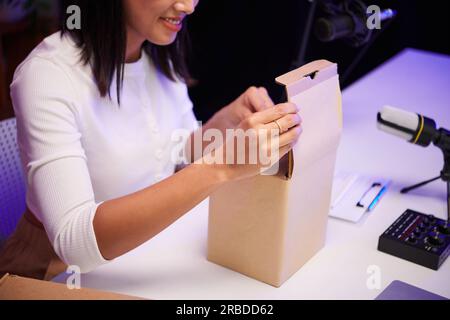 Immagine ritagliata di una donna eccitata che filma video di unboxing per il suo canale Foto Stock