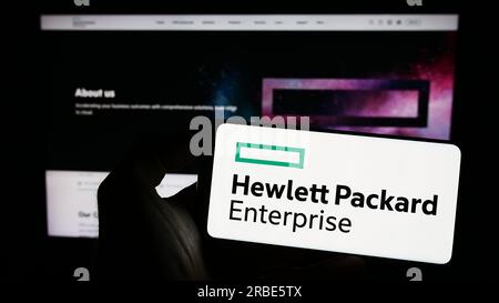 Persona che possiede uno smartphone con il logo aziendale Hewlett Packard Enterprise Company (HPE) sullo schermo davanti al sito Web. Concentrarsi sul display del telefono. Foto Stock