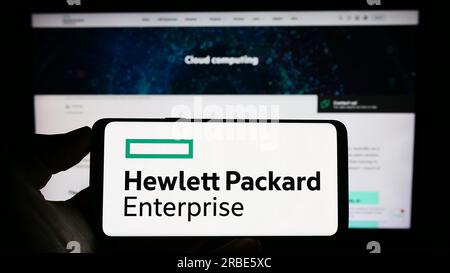 Persona che possiede il cellulare con il logo di Hewlett Packard Enterprise Company (HPE) sullo schermo davanti alla pagina Web aziendale. Concentrarsi sul display del telefono. Foto Stock