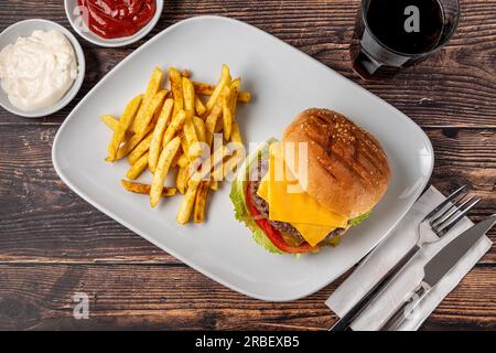 Cheeseburger con pomodori e Pickles con patatine fritte e ketchup Foto Stock