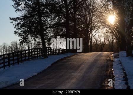 Il sole del tardo pomeriggio splende attraverso i rami degli alberi sopra una strada di campagna a Goshen, New Y., il 7 gennaio 2022. Foto Stock