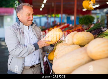 Uomo scelta melone fresco sul mercato Foto Stock