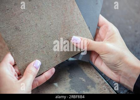 Campioni di pietra naturale per la produzione di pavimenti. Il processo di scelta del materiale per la pavimentazione. Primi piani di campioni di pietra nelle mani. Foto Stock