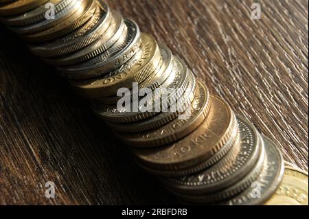 Bordi di monete diverse. Pile di monete di diversi paesi su un tavolo di legno scuro. Foto Stock