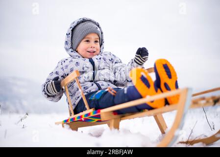 un bambino ama andare in slitta sulla neve in inverno Foto Stock