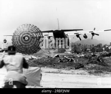 An Khe, Vietnam: Maggio, 1966 Un U.S. L'Air Force C-130 Hercules fornisce rifornimenti agli Stati Uniti Army 1st Calvary Division che utilizza il Low Altitude Parachute Extraction System (LAPES), dove l'aereo da carico arriva a un'altitudine di cinque piedi e i carichi vengono estratti dal retro dell'aereo da trasporto dal paracadute. Foto Stock