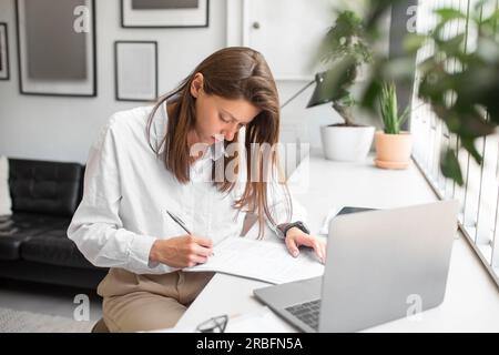 Carriera d'affari. Donna d'affari concentrata che firma un contratto o controlla i rapporti finanziari dell'azienda, che lavora in ufficio Foto Stock