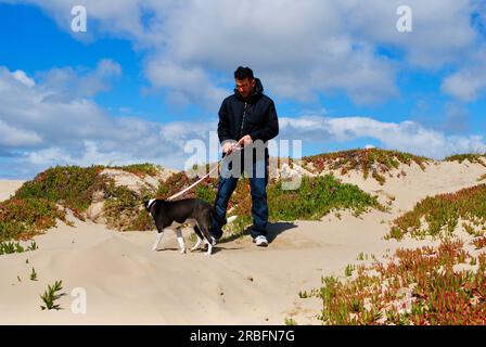 Un uomo cammina il suo cane sulla spiaggia di Pismo Beach, California. Foto Stock