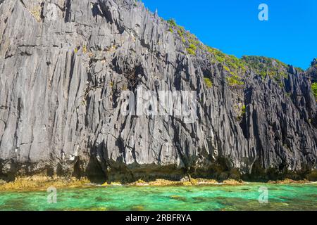 Una baia con rocce maestose a El Nido, Palawan nelle Filippine che sono sovrascresciute di arbusti e sorgono dall'acqua. Foto Stock