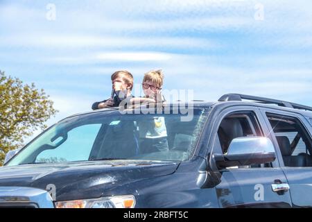 04 - 15 - 2020 Bartlesville Stati Uniti d' America - due giovani fratelli in piedi in SUV con la testa che fuoriesce dal tetto apribile guidando attraverso la natura - uno con gli occhiali le onde - Foto Stock