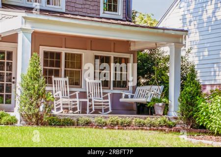 Porch America Porch Swing, due sedie a dondolo e un gatto Foto Stock