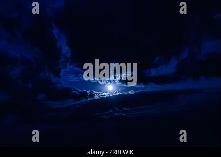 Vista della luna tra le nuvole nel cielo notturno Foto Stock