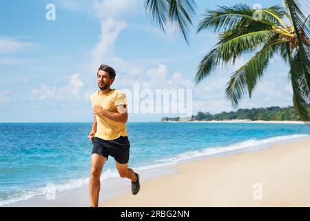 Giovane uomo che corre sulla riva del mare della spiaggia tropicale. Uno stile di vita sano e sport concept Foto Stock