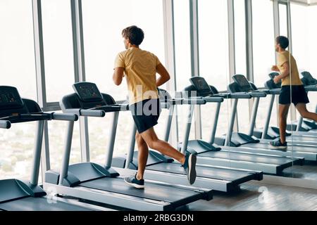 A piena lunghezza Ritratto di giovane uomo di sport in esecuzione su un tapis roulant in palestra. Fitness e di allenamento e di uno stile di vita sano concetto. A piena lunghezza Foto Stock