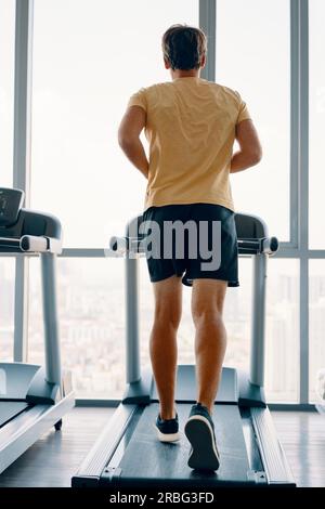 A piena lunghezza Ritratto di giovane uomo di sport in esecuzione su un tapis roulant in palestra. Fitness e di allenamento e di uno stile di vita sano concetto. A piena lunghezza Foto Stock