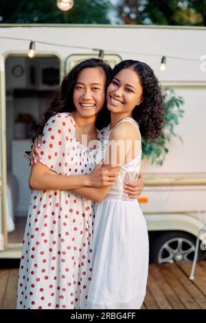 Sorridenti asiatiche e afro american donna abbracciando e hanno un grande tempo insieme. Donne amicizia concetto. Due migliori amici abbracciando all'aperto Foto Stock