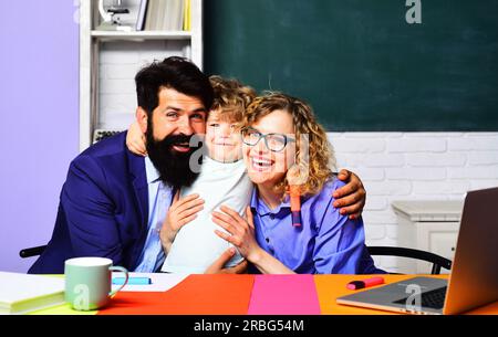 Piccolo scolaro in prima elementare. Ragazzo della scuola elementare. Processo educativo. Famiglia scolastica. Madre padre e figlio insieme a scuola. Maschio felice Foto Stock