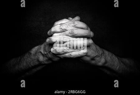 Le mani dell'uomo con le dita incrociate. Questo è un gesto classico di una persona che prega Dio nelle religioni cristiane Foto Stock