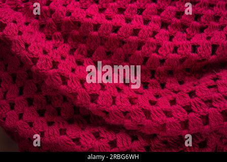 Soft pieghe di un caldo rosso maglia poncho di lana per essere utilizzate come sfondo Foto Stock