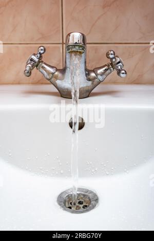 L'immagine verticale di un rubinetto con acqua fluente fortemente sotto pressione elevata Foto Stock