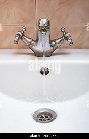 L'immagine verticale di un rubinetto con acqua che scorre lentamente durante un periodo di penuria Foto Stock