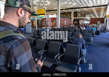 Un giovane viaggiatore chiama le forze dell'ordine dopo aver visto qualcosa di sospetto in un aeroporto internazionale Foto Stock