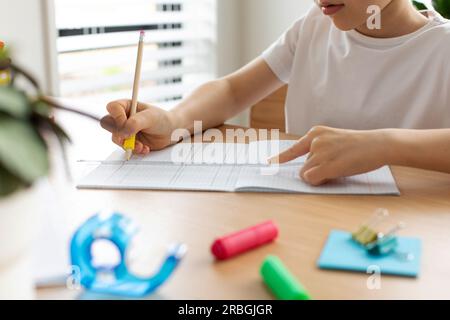 Un ragazzo carino crea un disegno con un righello e una matita. Lezioni a casa. Geometria e disegno. Foto Stock