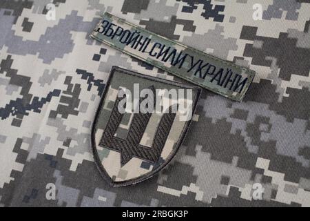 KIEV, UCRAINA - 6 ottobre 2022. Invasione russa in Ucraina 2022. Stemmi in uniforme dell'esercito ucraino su sfondo uniforme mimetico. Testo in ucraino - Foto Stock