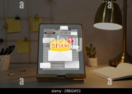 Messaggio di avviso spam nel software di posta elettronica. Illustrazioni delle buste che fuoriescono dal display del tablet sulla scrivania dell'ufficio Foto Stock