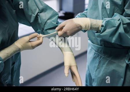 Colonia, Germania. 2 maggio 2023. Pirkko Schuppan (l), medico di chirurgia intima, indossa i guanti in sala operatoria. Crediti: Oliver Berg/dpa/Alamy Live News Foto Stock