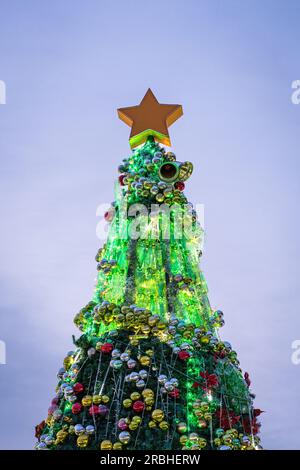 Albero di Natale decorato illuminato, con sfondo blu cielo serale. Foto Stock