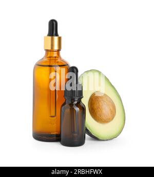 Bottiglie di olio essenziale e avocado tagliato su fondo bianco Foto Stock