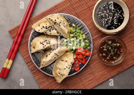 Deliziosi gyoza (gnocchi asiatici) serviti su un tavolo grigio, piatti Foto Stock