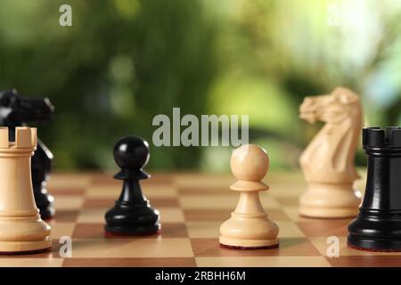 Pezzi di legno da scacchi sul tabellone da gioco su sfondo sfocato, primo piano Foto Stock