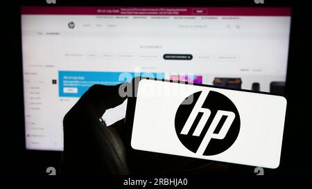 Persona che possiede uno smartphone con il logo della società informatica statunitense HP Inc. Sullo schermo davanti al sito Web. Concentrarsi sul display del telefono. Foto Stock
