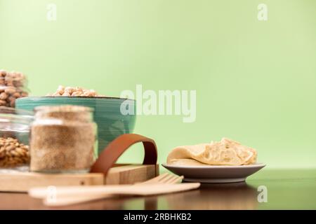 Hummus classico su un piccolo piatto su un tavolo di legno. Sfondo verde. Foto Stock