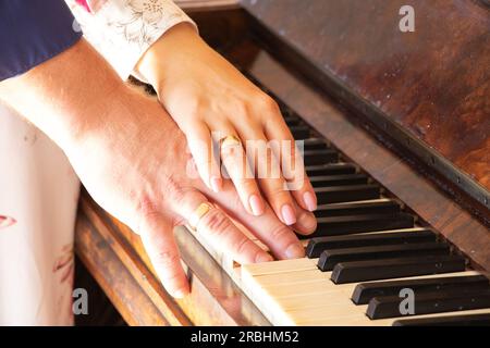 mani di sposi novelli con anelli d'oro sul piano primo piano, foto di nozze, anelli di nozze sulle dita Foto Stock