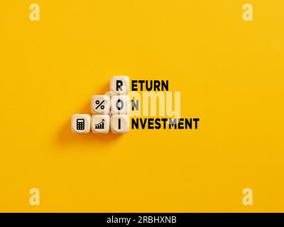 Il testo dell'acronimo ROI and Return on Investment (ROI e ritorno sull'investimento) su cubi di legno su sfondo giallo. Foto Stock