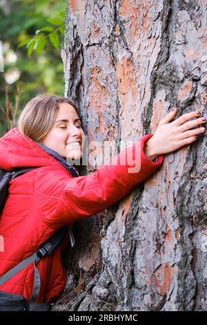 Ambientalista sorridente che abbraccia un albero nella foresta. Foto Stock