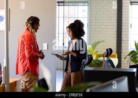 Due diversi colleghi di lavoro occasionali con un tablet in ufficio che parla, spazio per le copie. Lavoro di squadra, lavoro, affari, comunicazione, riunioni e casual Foto Stock