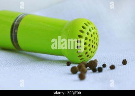 Grani di pepe nero e spezie in antico mortaio metallico con pestello su fondo di lino. Vecchi elettrodomestici da cucina per la macinazione di spezie, noci, erbe, Foto Stock