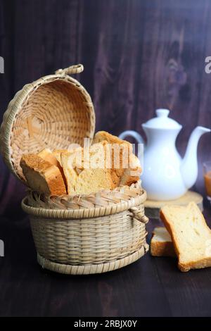 Tè Time snack. Salutare rusk di grano servito con tè di masala caldo indiano e brocca di latte su sfondo nero. Conosciuto anche come Mumbai cutting chai. Foto Stock
