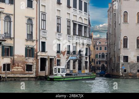 Raccolta rifiuti a Venezia. Edifici sul Canal grande, con barca per la raccolta dei rifiuti. Foto Stock