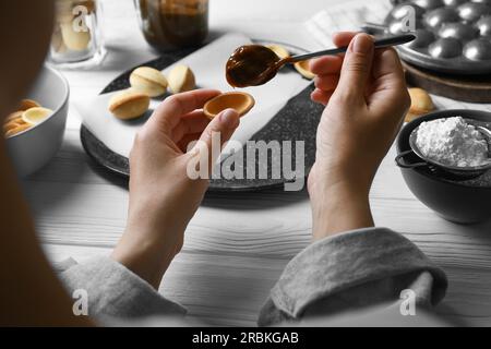 Donna che prepara deliziosi biscotti a forma di noce al tavolo di legno bianco, primo piano Foto Stock