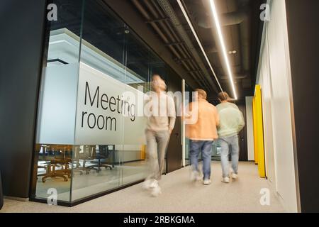 lunga esposizione di imprenditori di successo che camminano lungo la sala riunioni nel corridoio di un moderno ufficio di coworking con interni ad alta tecnologia e attività dinamiche Foto Stock