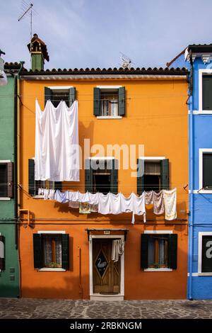 La lavanderia è appesa per asciugarsi all'esterno di una casa dai colori vivaci, Burano, Venezia, Italia, Europa Foto Stock