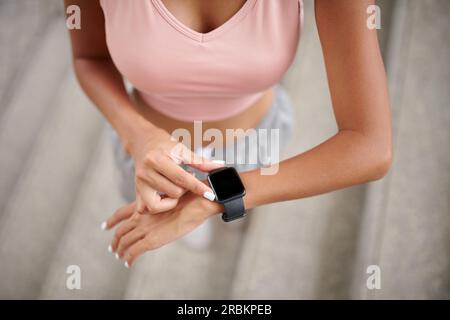 FIT Woman che controlla il battito cardiaco tramite app sullo smartwatch dopo la corsa mattutina Foto Stock